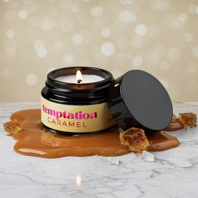 Vela perfumada Temptation Caramel em frasco preto com líquido caramelizado e pedaços de caramelo em superfície de mármore.