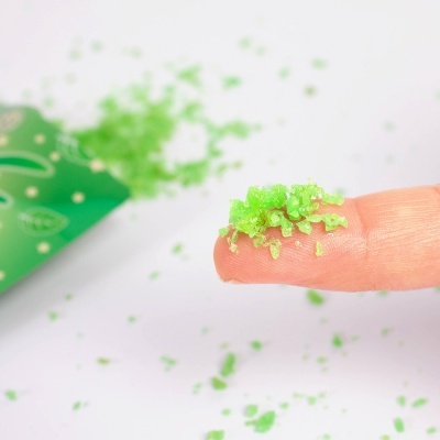 Sal verde em colisão sobre um dedo com embalagem verde ao fundo