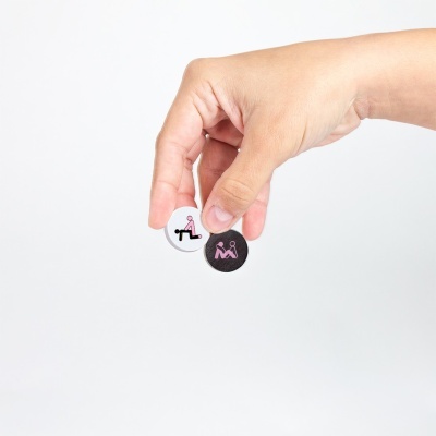 Mão a segurar dois discos pequenos, branco e preto, com desenhos de figuras humanas.