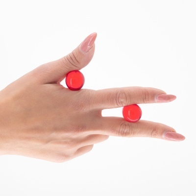 Mão com unhas postiças rosa clara a segurar esferas vermelhas.