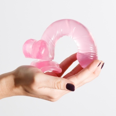 Mãos femininas segurando objeto cor-de-rosa translúcido em forma circular