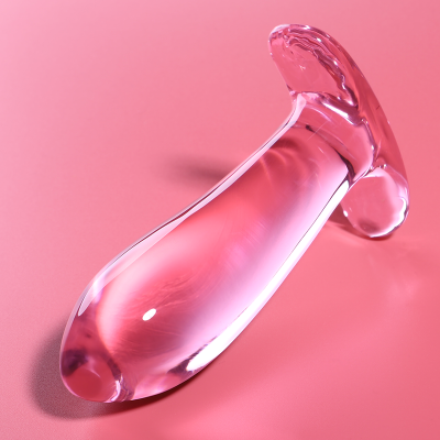 Sex toy de vidro transparente com base larga sobre fundo cor-de-rosa