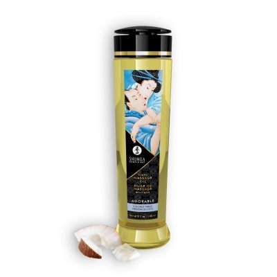 Frasco de óleo de massagem erótica Shunga com rótulo ilustrado e pedaços de côco ao lado