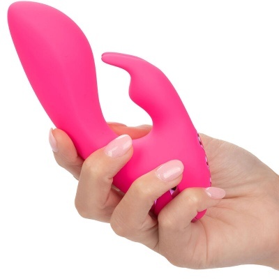Vibrador rosa anatómico de silicone numa mão com fundo branco