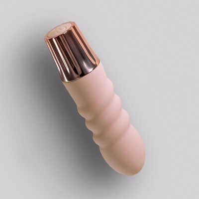 Frasco rosa claro com tampa metálica rose gold sobre fundo cinza claro.