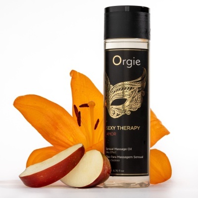 Frasco de óleo para massagem sensual preto e dourado com pétalas de flor laranja e fatias de maçã.