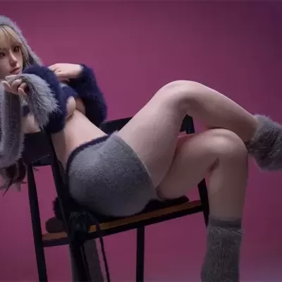 Boneca realista de lã cinza sentada em cadeira preta com fundo cor de vinho
