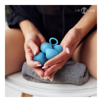 Objeto azul com bolhas e argola em mãos femininas sobre toalha cinzenta.
