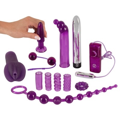 Conjunto de brinquedos sexuais roxos com uma mão a segurar um plug