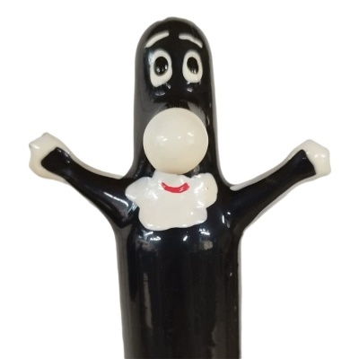 Boneco preto com detalhes brancos e boca vermelha, braços abertos