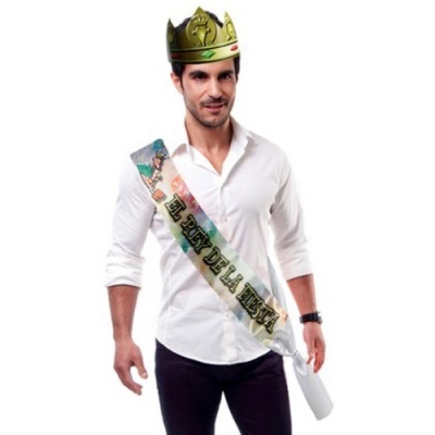 Homem com faixa colorida com texto EL REY DE LA FIESTA e coroa dourada de plástico