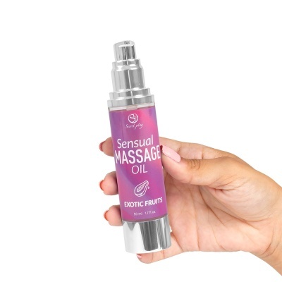 Frasco de óleo de massagem sensual de frutos exóticos com doseador prateado na mão
