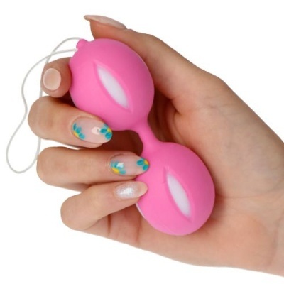 Mão segurando bola Ben Wa cor-de-rosa com cordão branco e unhas decoradas