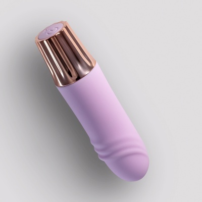 Produto lilás com parte metálica dourada rosa e fundo cinza claro