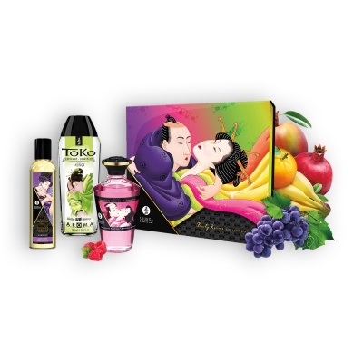 Conjunto de produtos eróticos Shunga com ilustração de casal na embalagem e frascos com rótulos variados, ao lado de frutas frescas.