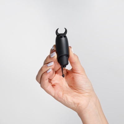 Dispositivo preto com forma de cabeça e chifres segurado por mão