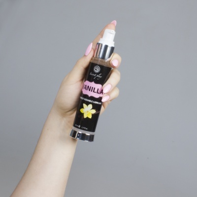 Frasco de lubrificante VANILLA nas mãos com unhas cor-de-rosa