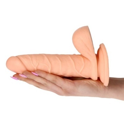 Dildo cor de pele com textura veiculada segurado por mão com unhas rosas, fundo branco