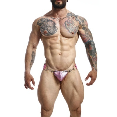 Homem musculado com tatuagens usando fio dental masculino cor-de-rosa com anéis metálicos