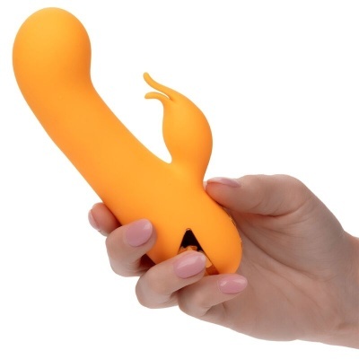 Mão segurando vibrador laranja em fundo branco