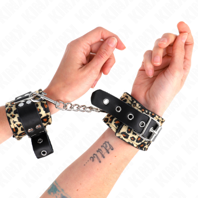 Par de algemas com padrão animal print e tiras de couro preto com corrente em punhos humanos.