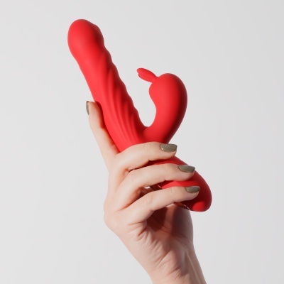 Vibrador vermelho de silicone com texturas onduladas segurado por mão feminina.