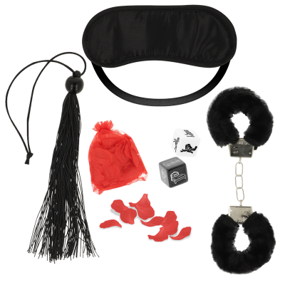 Conjunto de acessórios eróticos com venda preta, algemas com pelo preto, chicote preto e dados com saco vermelho.