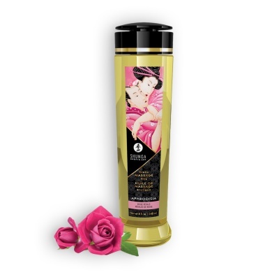 Frasco de óleo para massagem Shunga Aphrodisia com rótulo ilustrado e rosas cor-de-rosa ao lado
