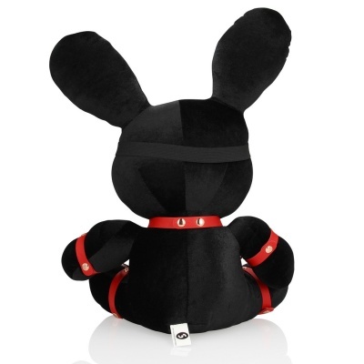 Peluche preto de coelho com alças vermelhas e faixa elástica preta visto de trás