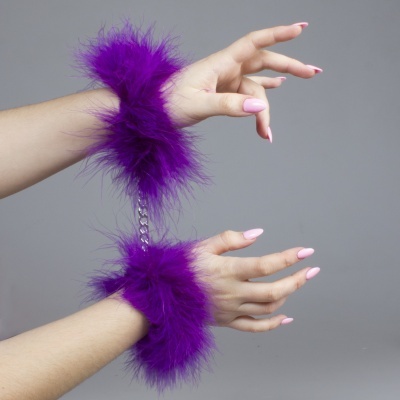 Algemas roxas com penugem em punhos femininos com unhas cor-de-rosa