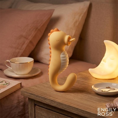 Figura decorativa cavalo-marinho amarela com detalhes laranja em mesa de madeira