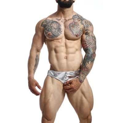 Homem musculado com sunga metálica prateada e tatuagens, fundo branco