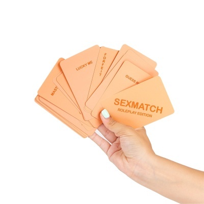 Mão segurando cartas cor de pêssego do jogo SEXMATCH ROLEPLAY EDITION