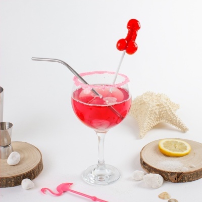 Copo com bebida vermelha, canudo metálico, pirulito vermelho em espetinho e decoração com conchas e limão