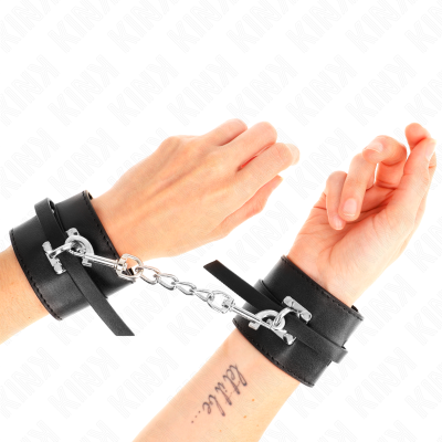 Mãos femininas com algemas de couro preto e correntes metálicas prateadas