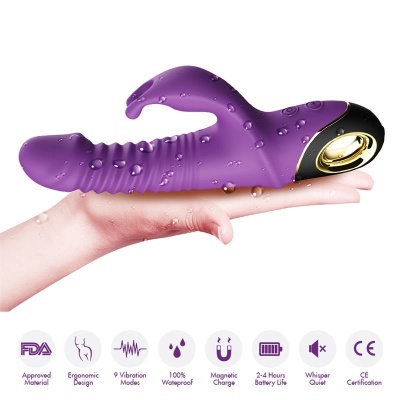 Vibrador roxo com parte preta e dourada, gotas de água, suportado em mão clara