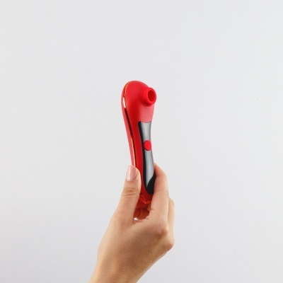 Dispositivo vermelho e preto segurado por uma mão em fundo branco.