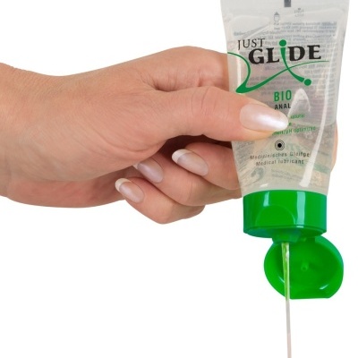 Mão segurando tubo de lubrificante transparente com tampa verde e líquido a sair