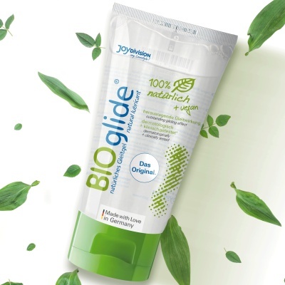 Tubo plástico branco e verde de lubrificante natural com folhas verdes ao redor.