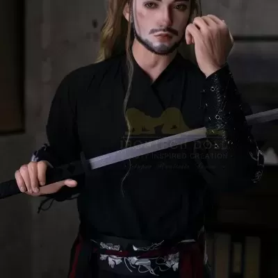 Boneco masculino realista com roupa preta e espada em fundo cinzento