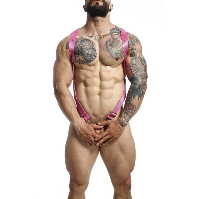 Homem musculado com arnês cor-de-rosa e tatuagens