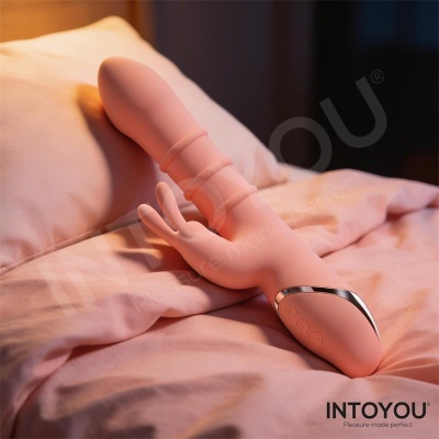 Vibrador rosa de silicone em forma de coelho sobre roupa de cama cor-de-rosa