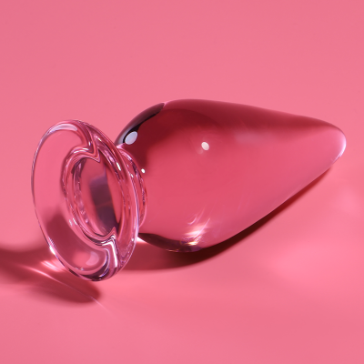 Plug anal transparente de vidro com base larga sobre fundo rosa