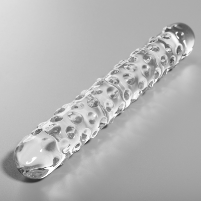 Cilindro de vidro transparente com textura de bolhas sobre superfície cinzenta