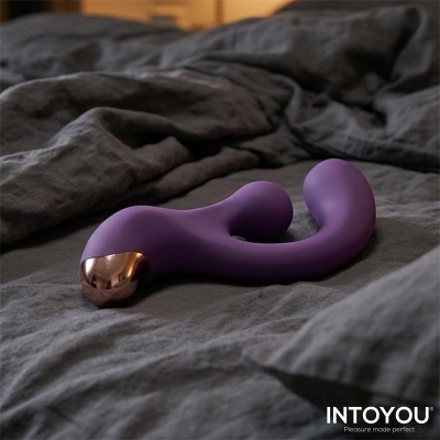 Vibrador roxo com extremidade dourada sobre tecido cinza escuro