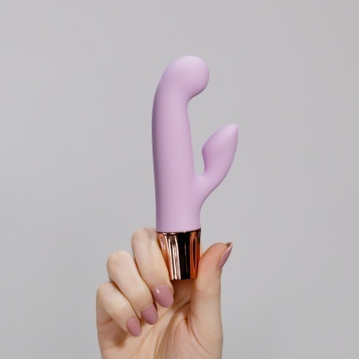 Mão segurando vibrador lilás com base dourada