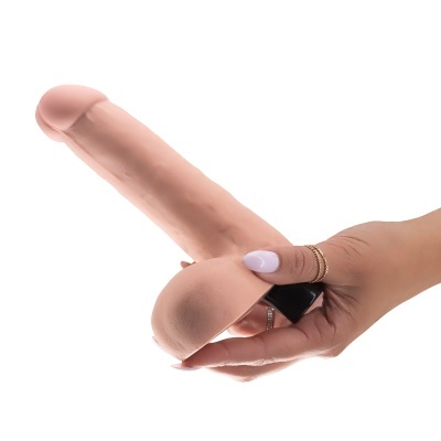 Mão feminina com anéis segurando dildo cor de pele