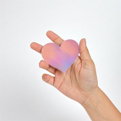 Mão segura coração rosa e roxo com fundo branco