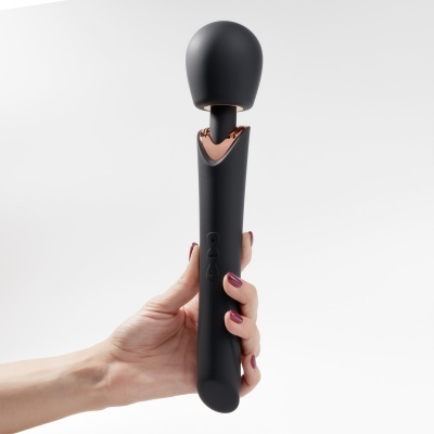 Massageador manual preto com detalhe cobre e mão segurando