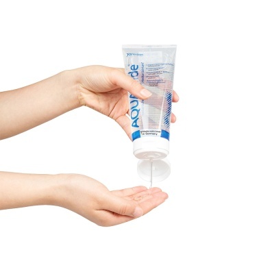 Duas mãos a verter gel transparente de um frasco AQUAglide